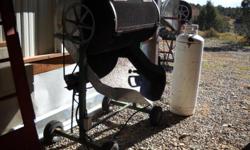 Two commercial size motorized chile roasters on wheels with sheet metal wind guarding, one red frame the other green. Both fully operational with two 25 gallon propane tanks, regulator and hoses. Currently stored in Roswell, you would have to make pick up