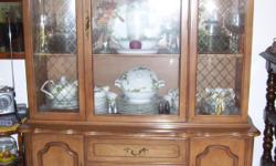 The china hutch has three drawers and two cabinets in the bottom. The top part has curved glass and has gold diagonal marks on the two side pieces of glass. It is a fruitwood honey color. It measures about 4 ft by 6 ft (about 48 in by 60 in) and is a