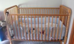 Jenny spindle crib has light oak finish. Used for grandchild only a few times. Features include double drop sides, rolling swivel casters, and four mattress positions. Includes posturepedic mattress and blue beddding set. Call 717-732-0794.