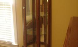 This is a oak, glass curio cabinet in wonderful condition. It stands at just under 6 feet tall. There are 3 slid-in glass shelves. There is a light at the top with electric plug-in. A small storage compartment at the bottom. This piece of furniture is