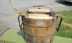 This is an antique mop bucket and wringer combination from Ole Woodenware Manufacturing Company. The precise age of the piece is uncertain, however the construction is primarily of wood which has a great dark patina, implying the progress of decades,
